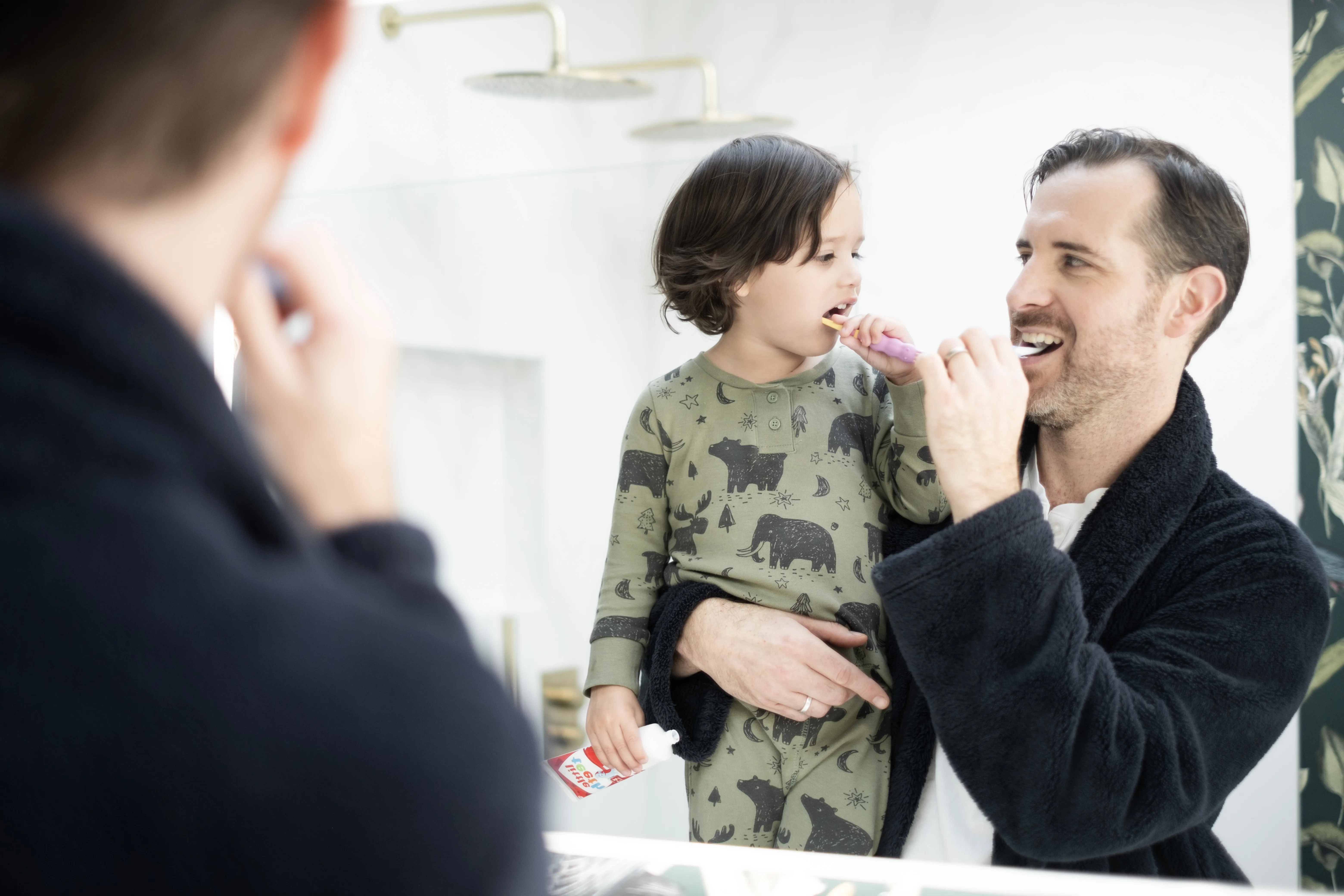 A father and his child brushing their teeth together