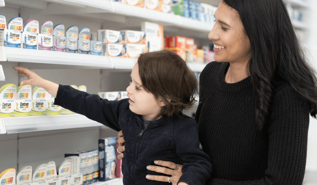Child reaching out for product in pharmacy and woman smiling