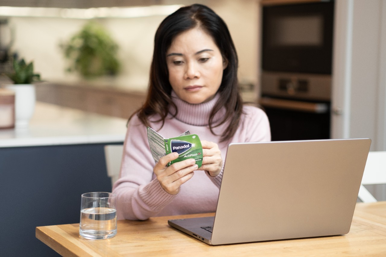 A woman reading the instruction inside a Panadol package