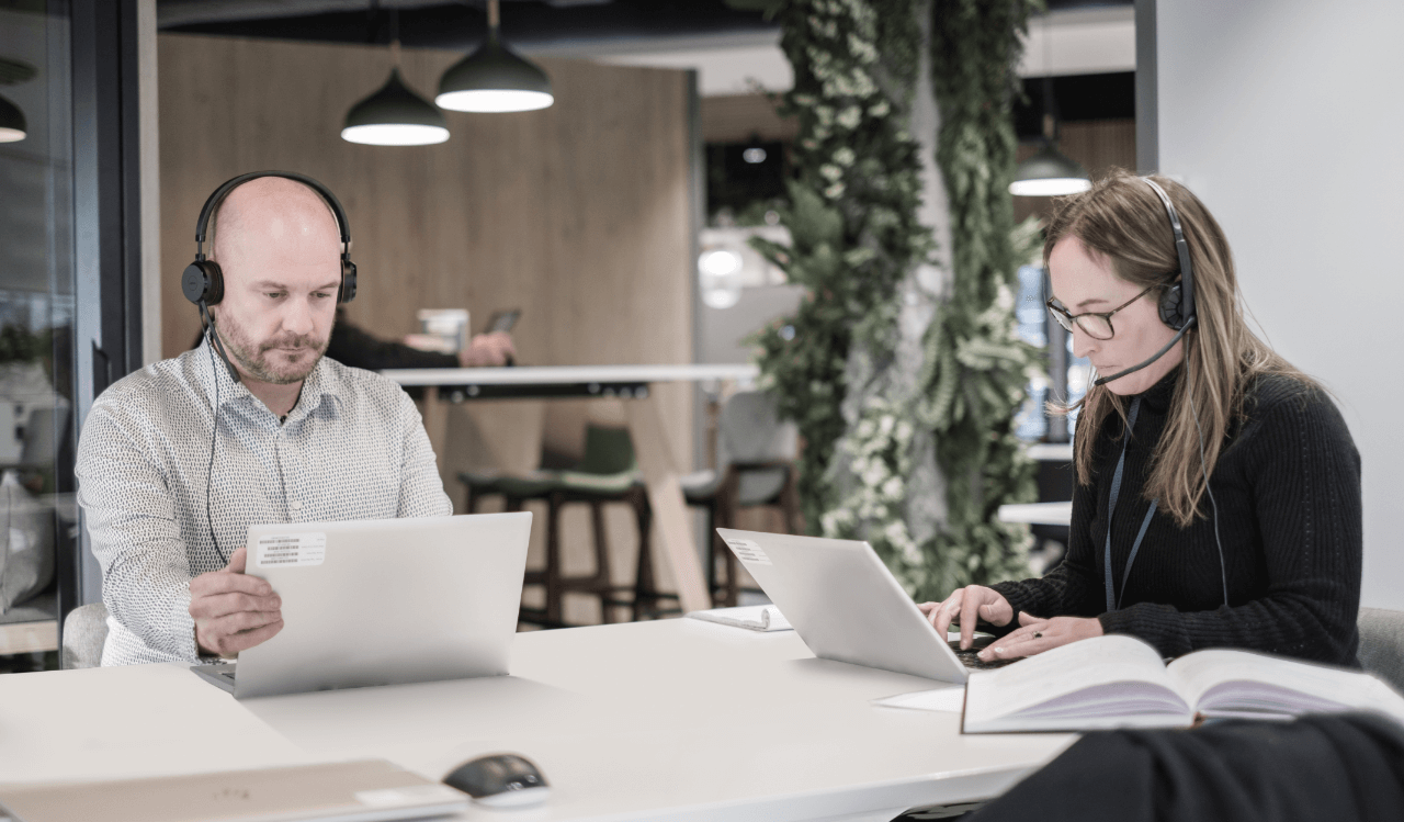Man and woman walking on laptops with headphones