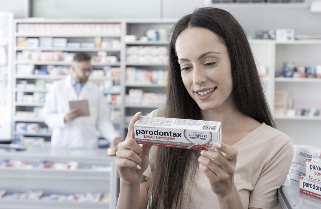 Woman browsing products and checking the back of a Poligrip package