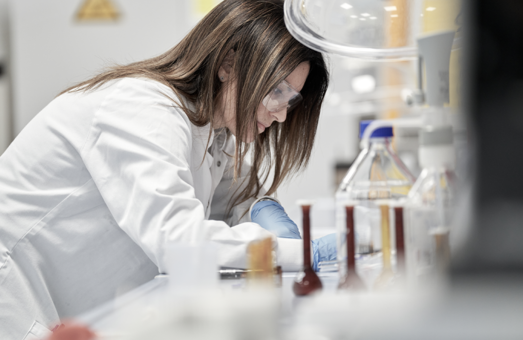 Smiling woman in Haleon coat and protective gear, working in lab/manufacturing setting