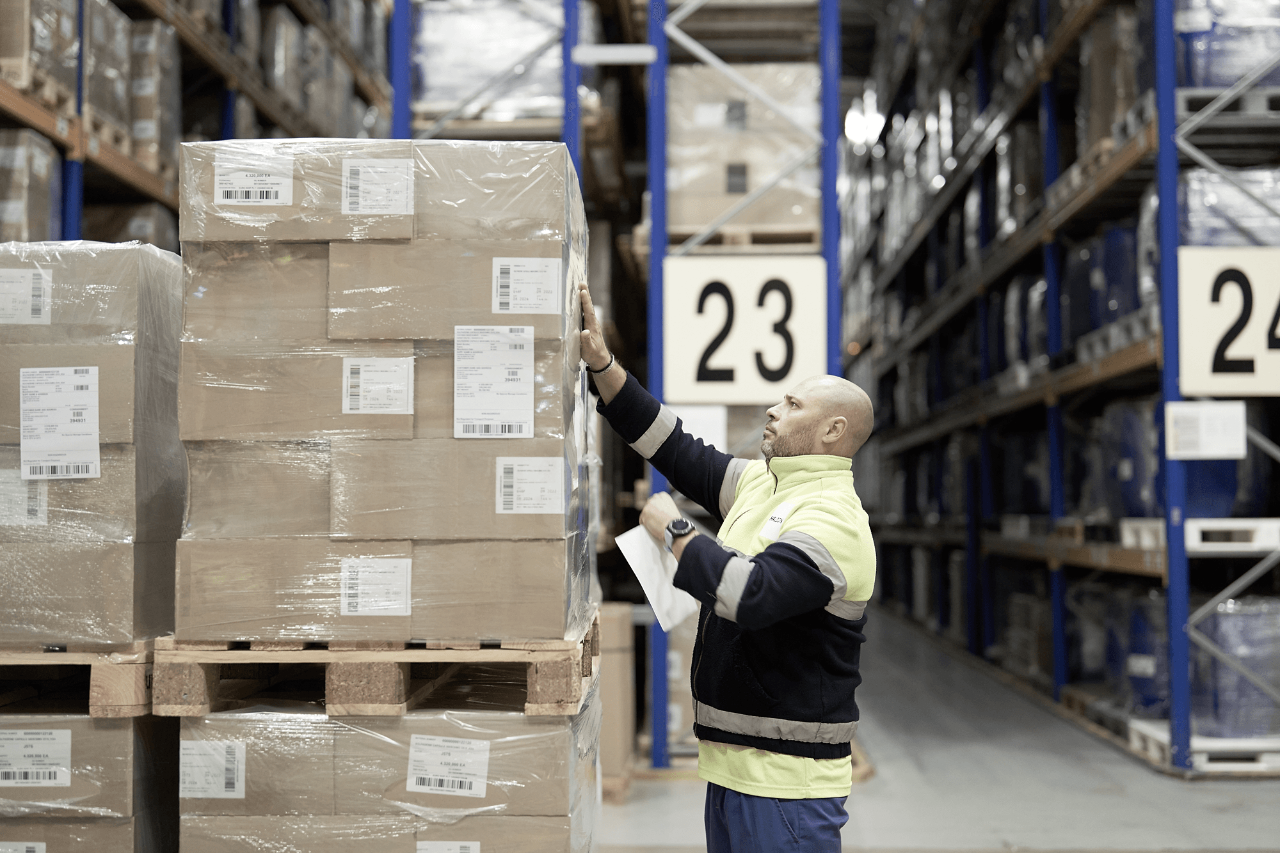 Warehouse worker handling boxed goods on pallet racking