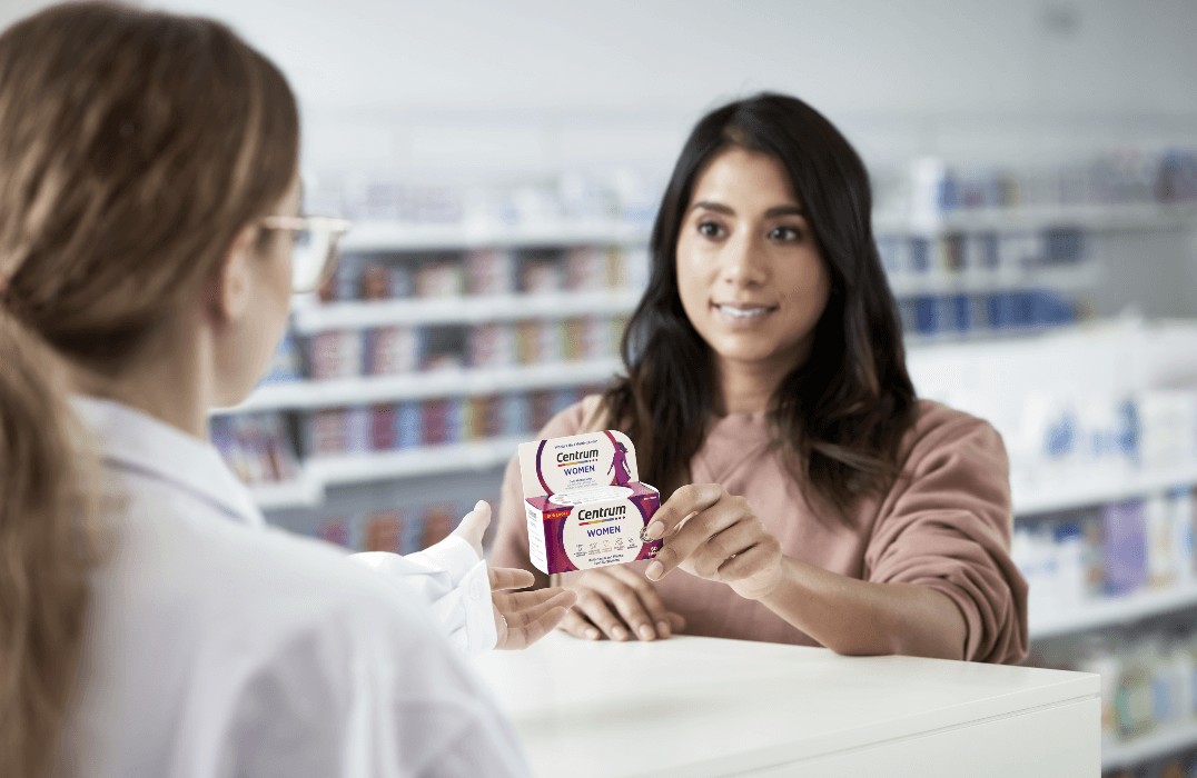 Female customer next to the counter in a shop holding packet of Centrum