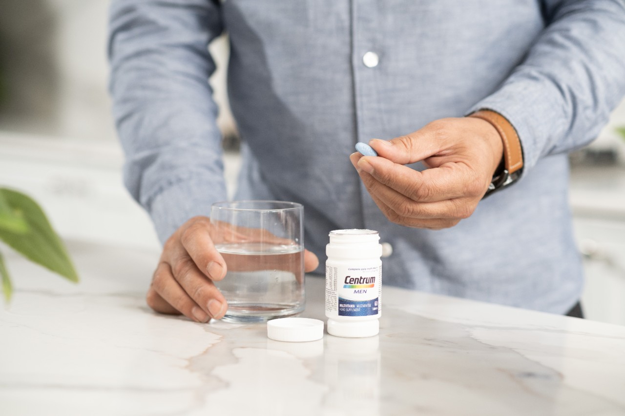 Man about to take a pill from Centrum Men