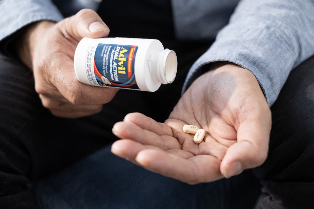 Person pouring Advil pills from a container into their hand