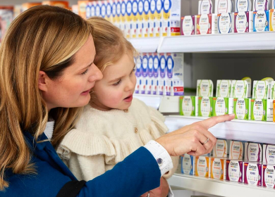 Mother and daughter in supermarket. Mother pointing Centrum on shelf