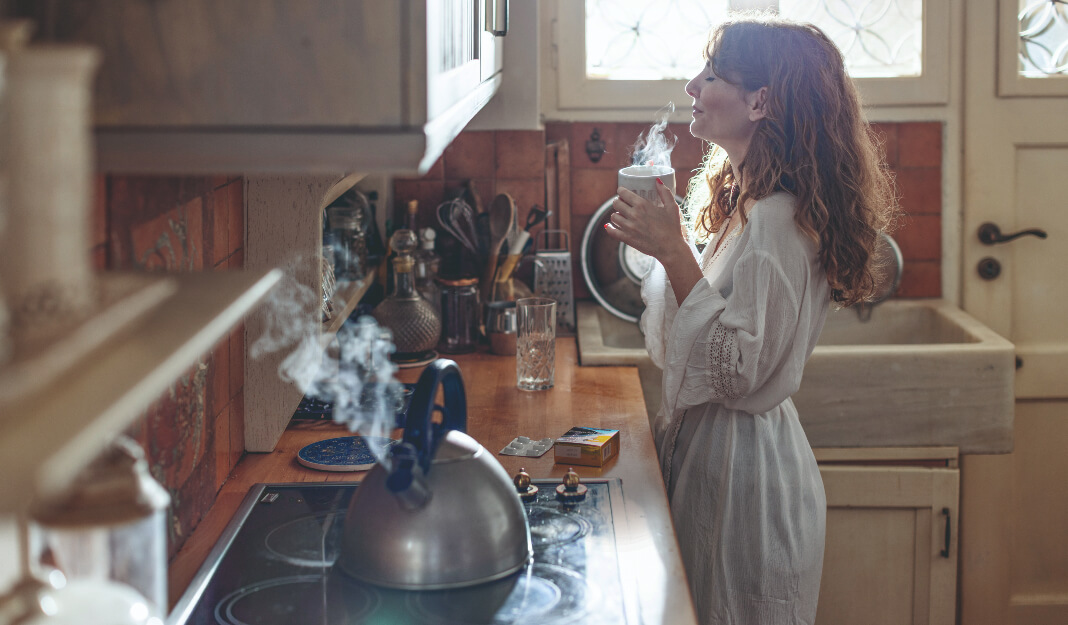 Person in a kitchen near a steaming kettle.