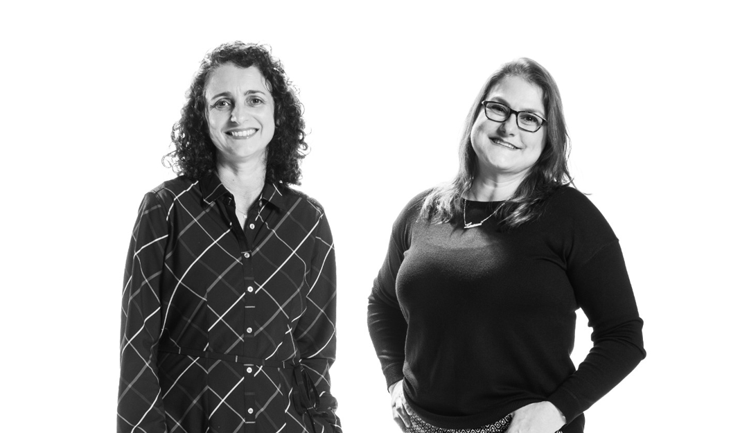A black and white frontal picture of two women smiling 