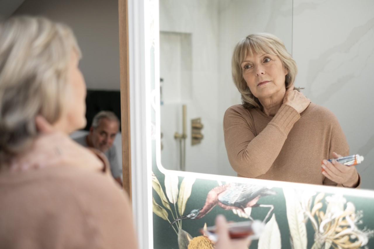 Woman putting cream on neck