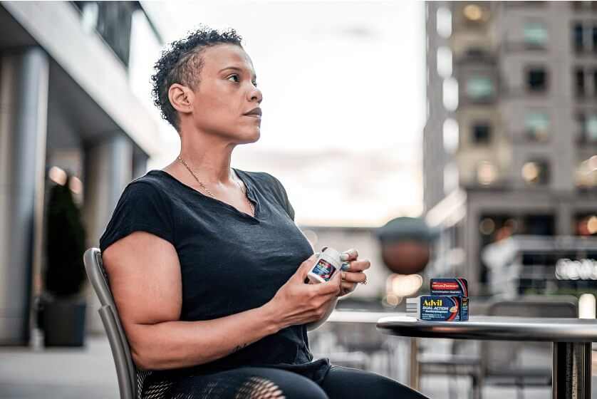 Woman sitting down holding Advil