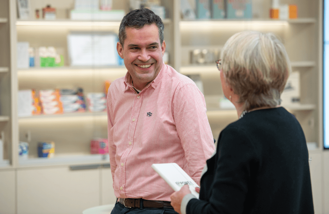 Two individuals conversing in a healthcare retail setting.