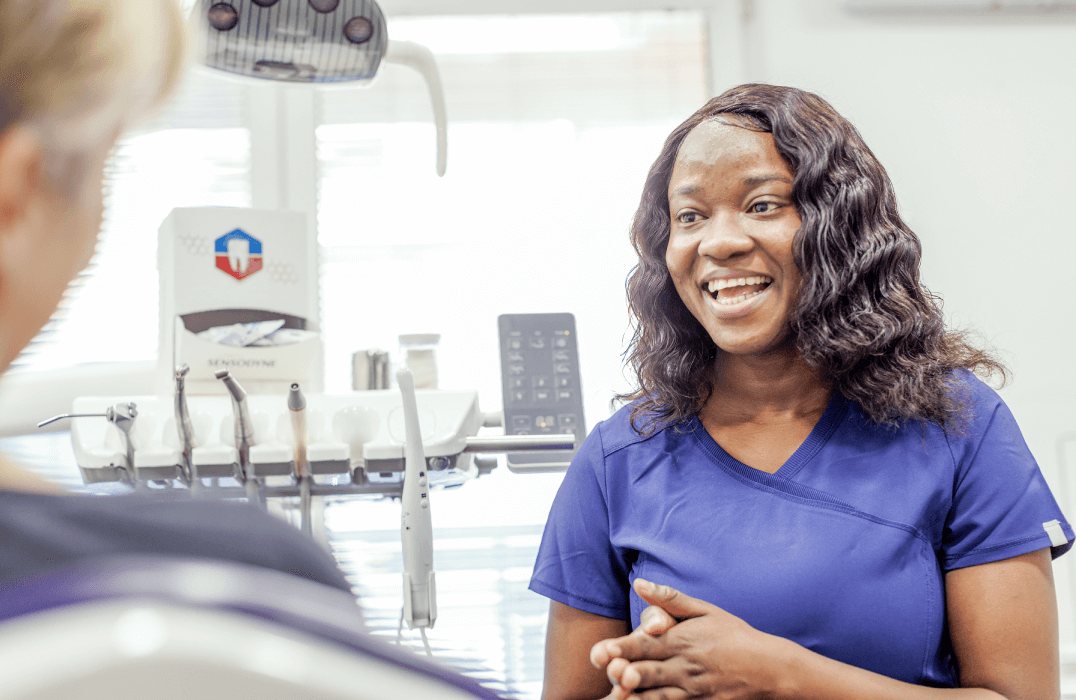 Healthcare professional speaking with a person in a clinical environment, with equipment visible behind them