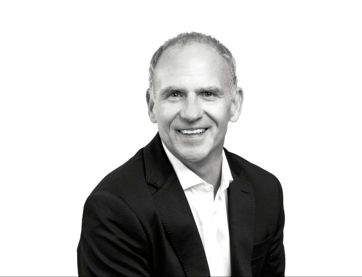 A headshot of Sir Dave Lewis, the image is in black and white
